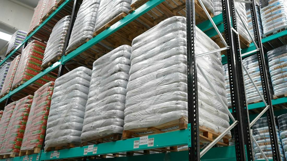 Stretch-wrapped pallets of goods in pallet racking, with location labels on the beams